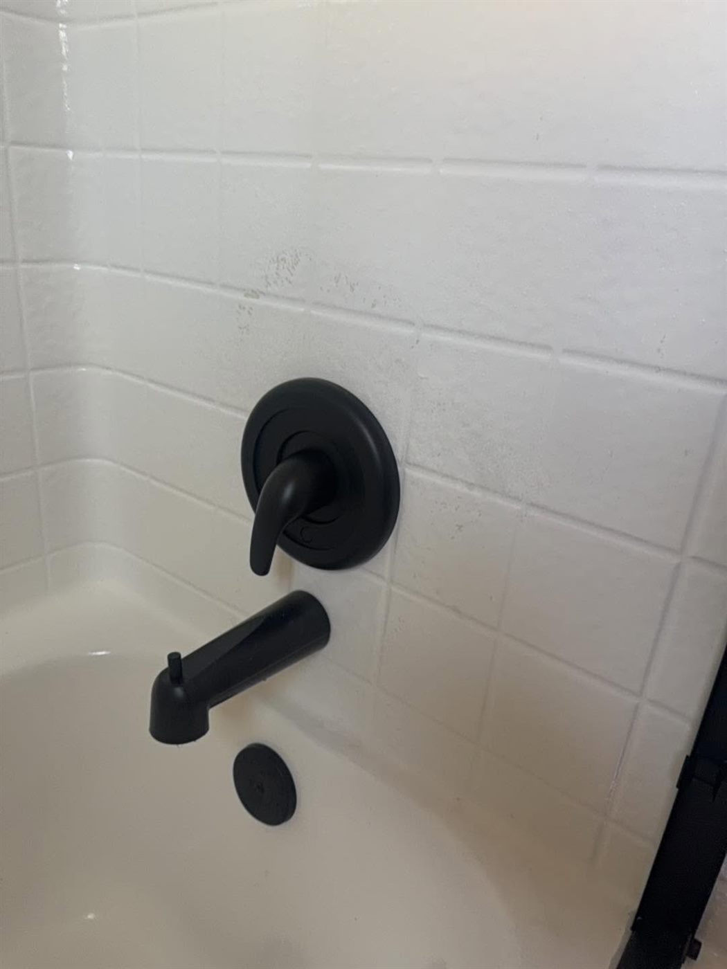 Black tub spout and valve trim on a fresh surround