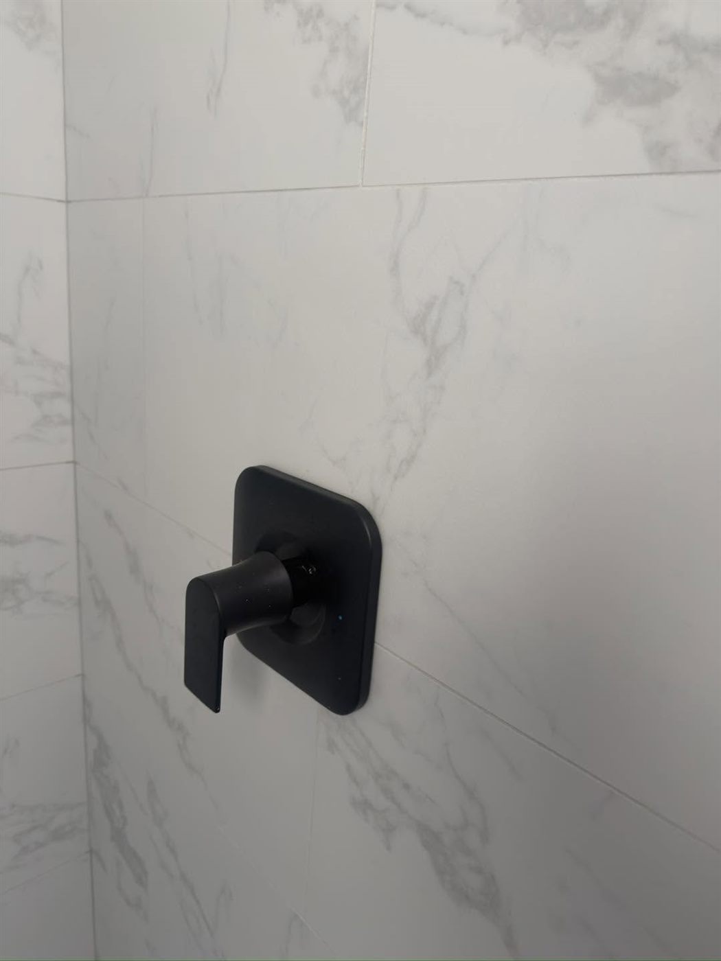 Black shower valve on marble tile